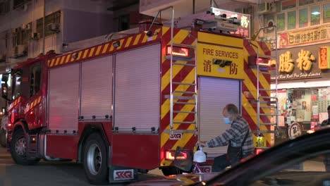 A-firetruck-is-seen-stationed-in-the-street-as-vehicles-drive-through-while-an-emergency-unit-team,-firefighters,-respond-to-a-distress-call-in-Hong-Kong