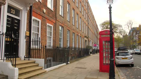 Iconic-Red-Telephone-Booth-Symbolizing-British-Heritage-On-The-Sidewalk-Along-The-Street-In-London,-UK