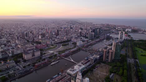 Dolly-in-aerial-view-of-the-city-of-Buenos-Aires-with-the-Puente-de-la-Mujer-and-the-touristic-area-of-Puerto-Madero,-blue-hour