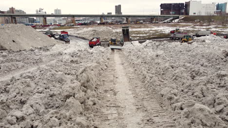 Multiple-Specialized-Tractors-And-Trucks-Bring,-Unload-and-Gather-Snow-Removed-form-City-Streets-in-Suburb-Areas-After-Winter-Storm