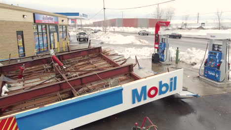 Fallen-roof-of-gas-station-after-winter-storm-in-Buffalo,-aerial-rise