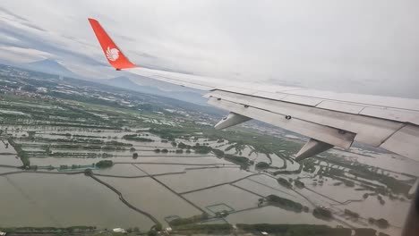 Flugzeug-Steigt-über-überschwemmter-Landschaft-Indonesiens-Mit-Löwengruppenlogo-Auf