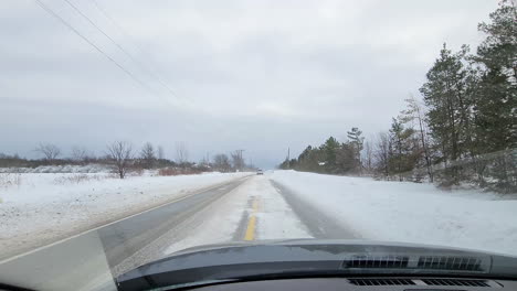 POV-From-Inside-Car-Driving-Along-Snow-Covered-Road,-passing-by-cars-stuck-in-Snow
