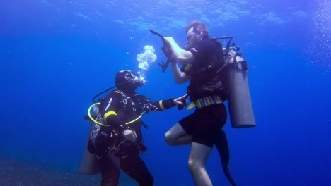 Two-scuba-divers-in-the-blue-ocean-with-all-their-diving-gear