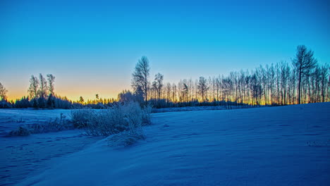 Nighttime-to-golden-yellow-sunrise-time-lapse-over-a-snowy,-winter-landscape