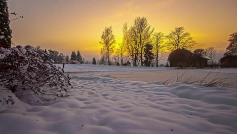 Brilliant-orange-sunset-to-darkness-time-lapse-at-a-cabin-by-a-frozen-lake-and-snowy-landscape