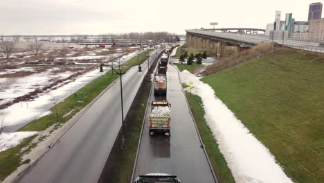 Forward-aerial-of-queue-of-snow-dump-trucks-after-storm-in-Buffalo,-NY