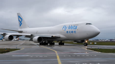 Fly-Meta-Cargo-Jumbo-B747-Airplane-Taxiing-at-the-Airport,-Cloudy-Day