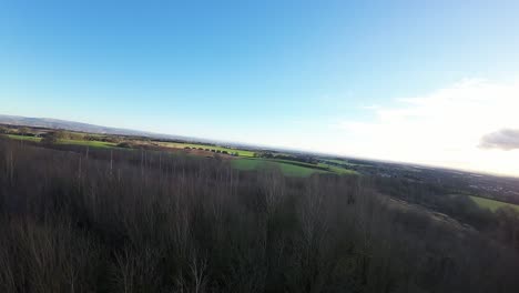 FPV-drone-flying-across-Billinge-hill-beacon-autumn-trees-and-Lancashire-farmland-landscape