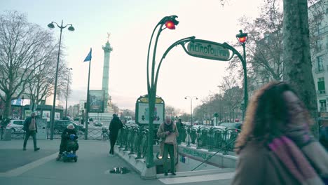 Vistiendo-Ropa-De-Abrigo,-Gente-Caminando-Por-Las-Calles-De-La-Plaza-De-La-Bastilla-En-La-Isla-De-Francia,-Gente-Tomando-El-Metro-Para-Moverse,-París,-Francia