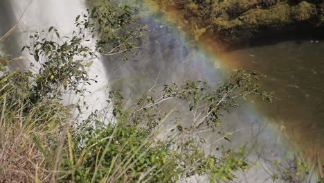 Regenbogen-Bildet-Sich-Um-Den-Wasserfall-Im-Wald,-Umgeben-Von-Grünen-Büschen