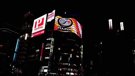 Illuminated-Billboard-Signs-of-Advertisement,-Evening-in-Tokyo-Japan,-Pan-shot