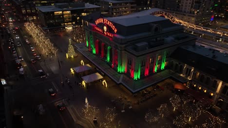 Denver-Union-Train-Station-Colorado-En-La-Noche-Iluminada-Durante-La-Navidad,-Vista-Aérea-Hacia-Atrás-De-Luces-Coloridas-En-El-Distrito-Del-Centro