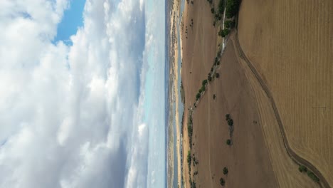 Vertical-video-of-rural-landscape-of-Mourão,-river-beach-along-farmland-fields,-Alentejo