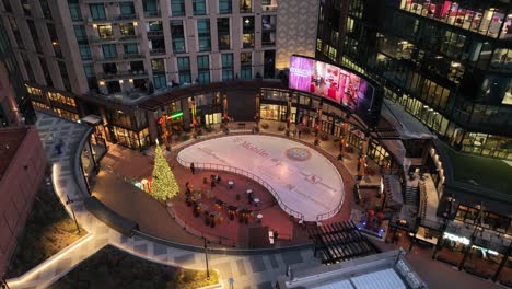 Vista-Aérea-Nocturna-De-La-Plaza-Mcgregor-En-Denver,-Colorado,-Con-Una-Pista-De-Hielo-Al-Aire-Libre-Y-Un-árbol-De-Navidad-Iluminado