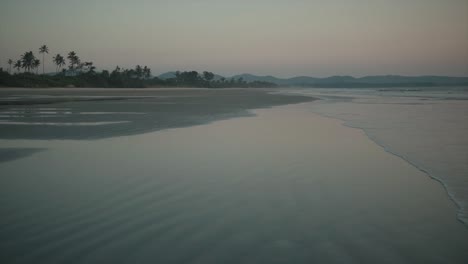 Beautiful-empty-beach-with-small-waves-gently-crashing-against-the-shore-at-dawn