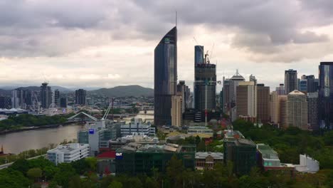 Aerial-drone-flyover-QUT-gardens-point-campus-in-downtown-central-business-district,-panning-view-capturing-south-bank-parkland-recreational-precinct-across-the-river,-Brisbane-city,-Queensland