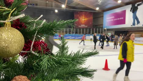 Cerca-Del-árbol-De-Navidad-Con-Mucha-Gente-Patinando-Sobre-Hielo-En-La-Pista-Cubierta-En-Segundo-Plano.