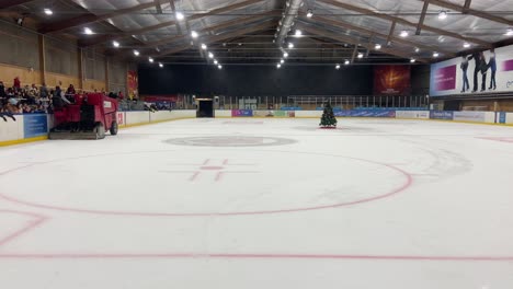 Machine-smoothing-ice-on-an-indoor-ice-rink-while-people-wait-to-go-out-to-skate