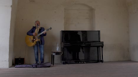 Matera,-Artista-Callejero-De-Italia-Tocando-La-Guitarra-Directamente-Con-El-Piano-A-Su-Lado