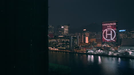 Aerial-revealing-shot-of-Harbourside-HQ-building-and-Children's-hospital-in-Kwun-Tong-district-at-night-in-Hong-Kong