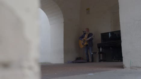 Matera,-Italien-Straßenkünstler,-Der-Gitarre-Spielt,-Mit-Klavier-Neben-Ihm-Seitenansicht-Rack-Fokus-Niedrige-Ansicht