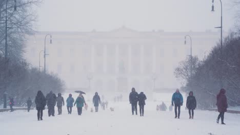 People-Walking-Through-Heavy-Snow-Along-Palace-Grounds-In-Front-Of-Det-kongelige-Slott-In-Oslo