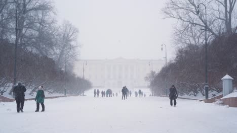 Heavy-Snow-Falling-Along-Palace-Ground-Path-With-Visitors-Leading-Towards-Royal-Palace-In-Oslo,-Norway