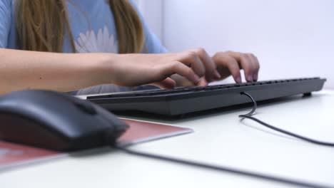 young-girl-learning-to-use-computer,-hand-goes-from-mouse-to-keyboard,-defocus-slow-motion