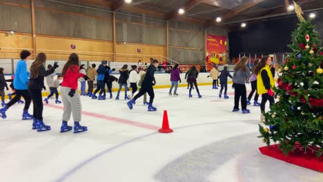 Static-view-of-many-people-including-lot-of-kids-ice-skating-in-indoor-rink-in-Madrid,-Spain