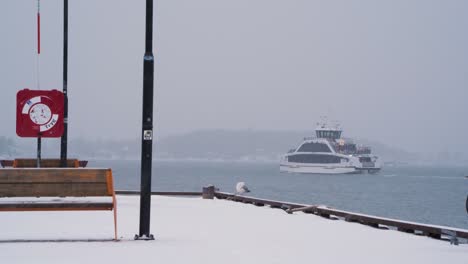 Vista-Desde-El-Muelle-De-Aker-Brygge-Del-Barco-De-Pasajeros-Dronningen-Que-Sale-Del-Puerto-En-Un-Día-De-Nieve-Nublado-En-Oslo