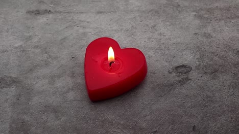 Red-heart-shaped-candle-and-candlelight-isolated-on-stone-background-4K
