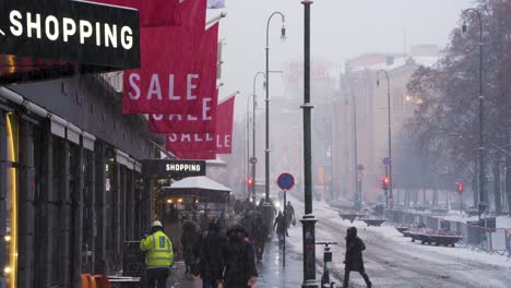 Einkaufsschilder,-Die-Während-Des-Winterschneefalls-über-Den-Geschäften-Entlang-Der-Karl-Johans-Gate-Road-Hängen-Und-Passanten-Vorbeigehen