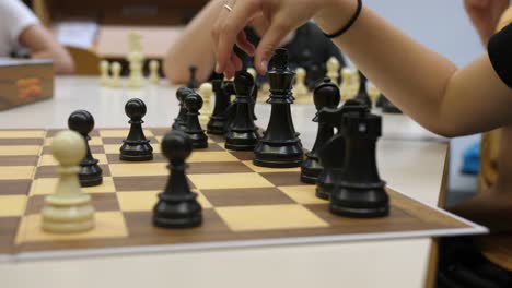 Kinder-Haben-Spaß-Beim-Schachspielen,-Nahaufnahme-Einer-Sich-Bewegenden-Figur-Mit-Verschwommenem-Hintergrund