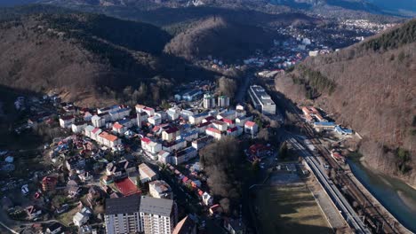 Aerial-tilt-down-shot-over-small-residential-area-of-Sinaia-in-sunlight---Mountain-road-with-driving-cars