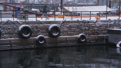 Nieve-Cayendo-Sobre-Neumáticos-De-Goma-Colgando-De-La-Pared-En-El-Puerto-Deportivo-De-Aker-Brygge-Para-Proteger-A-Los-Barcos