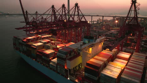 Ein-Riesiges-Maersk-Linienschiff-Liegt-In-Hongkong-Vor-Anker,-Während-Einer-Der-Roten-Kräne-Einen-Maersk-Container-Anhebt,-Um-Die-Kiste-Am-Kai-Zu-Entladen