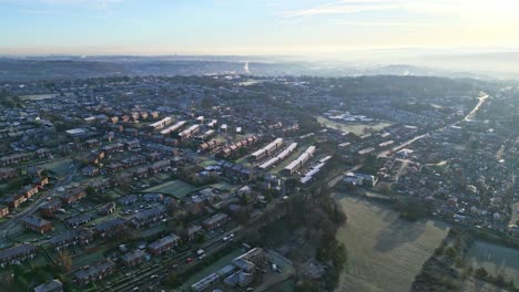 Very-cold-winter-aerial-footage-of-a-town-city-landscape,-with-low-afternoon-lighting-and-freezing-sunlit-houses