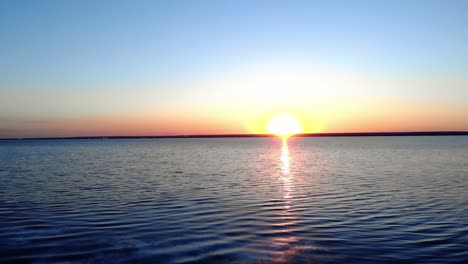 Pulsierendes-Sonnenlicht-Eines-Sonnenaufgangs,-Der-Sich-In-Einem-Ruhigen-See-Widerspiegelt