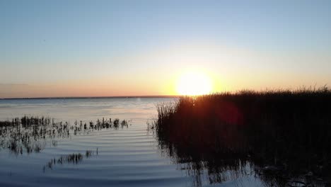 Goldener-Sonnenaufgang-Mit-Spiegelreflexion-Auf-Einem-Ruhigen-See