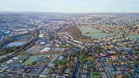 Winter-aerial-footage-of-a-frost-covered-urban-town-of-Dewsbury-Moor-and-Heckmondwike,-Yorkshire-UK,-showing-busy-roads,-fishing-lake,-traffic-and-red-brick-houses