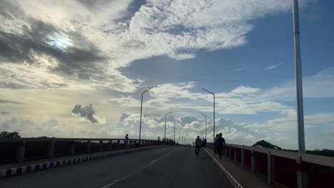 POV-from-vehicle-passing-over-bridge-towards-cloudy-blue-sky