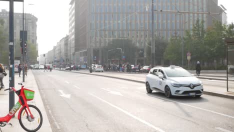 Cars-driving-din-downtown-Milan-on-sunny-day,-handheld-view