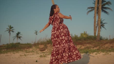 Una-Mujer-Caucásica-Despreocupada-Girando-Alrededor-Bailando-En-Una-Playa-Con-Un-Vestido-Floral-Rojo-De-Verano-En-Un-Hermoso-Día-Soleado-Al-Aire-Libre,-India