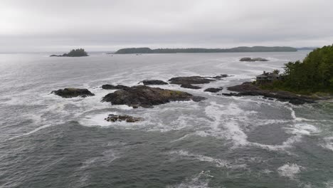 The-rugged-BC-coastline,-ocean-waves-crashing-on-rocks-and-the-beach-in-Tofino-British-Columbia