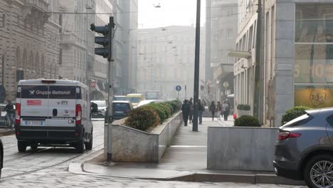 Milan-city-cars-driving-and-pedestrians-walk-on-sideway,-handheld-view