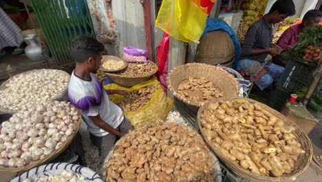 Street-market-vendor-in-Dhaka,-Bangladesh-with-piles-of-ginger-garlic-basket