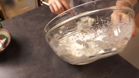Zoom-in-close-up-shot-of-a-young-woman-mixing-the-egg-white-foam-into-the-mixture-of-butter-and-honey-preparing-a-honey-cake-filling