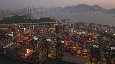 Weitwinkel-Drohne-Schoss-Nach-Sonnenuntergang-Vom-Verkehr,-Der-über-Eine-Hochstraße-Fährt,-Mit-Einem-Großartigen-Blick-Auf-Die-Skyline-Von-Hongkong-Und-Den-Containerhafen