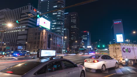 Nächtlicher-Autoverkehr-Zeitraffer-An-Der-Kreuzung-Der-Gwanghwamun-Station-Und-Personen,-Die-Die-Straße-Auf-Dem-Zebrastreifen-überqueren